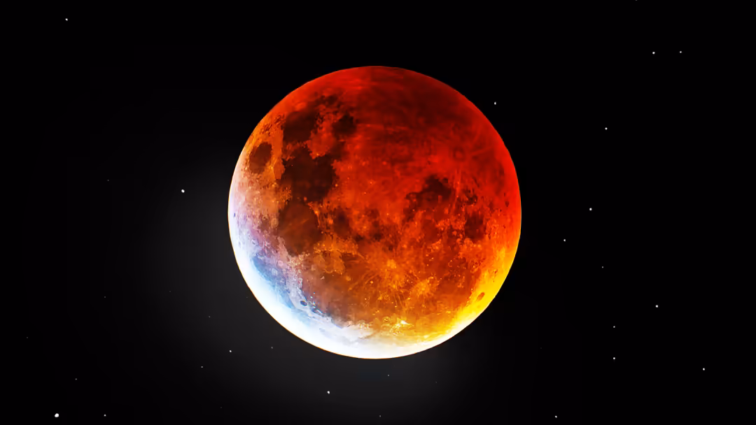 A vivid blood moon with red and orange hues during lunar eclipse, surrounded by stars against a black night sky