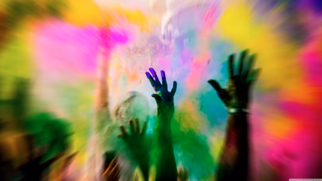 Silhouetted hands reaching upward in vibrant rainbow blur of pink, yellow, green, purple and cyan colors creating dynamic ene