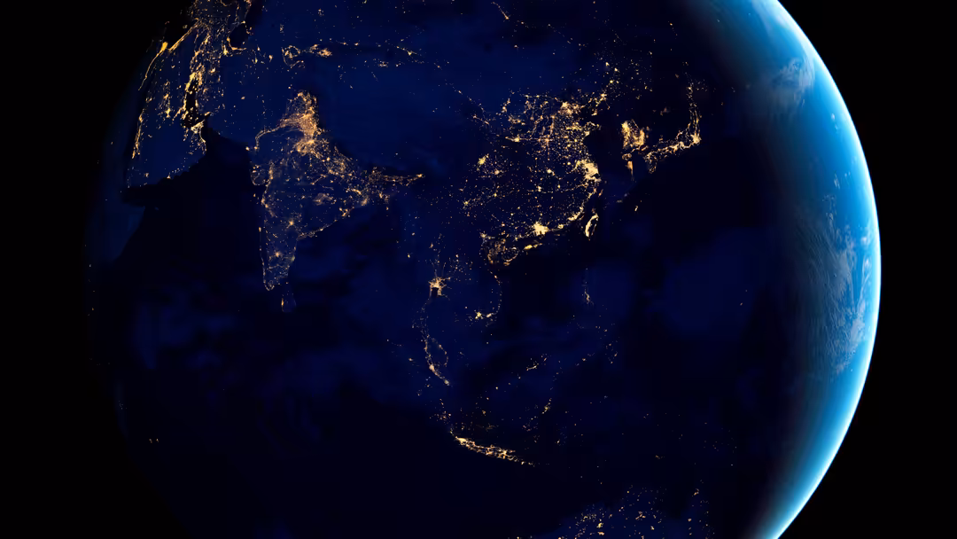 Earth at night with golden city lights illuminating continents across blue planet against black space background