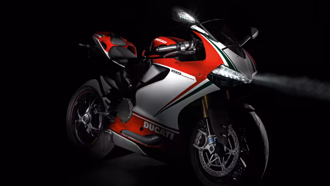 Red and white Ducati sportbike with Italian flag striping against dark background, featuring LED headlights and racing design