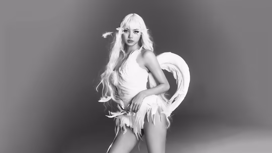 Portrait of Lisa with long platinum blonde wavy hair and white feathered angel wings, wearing white clothing against a gray g