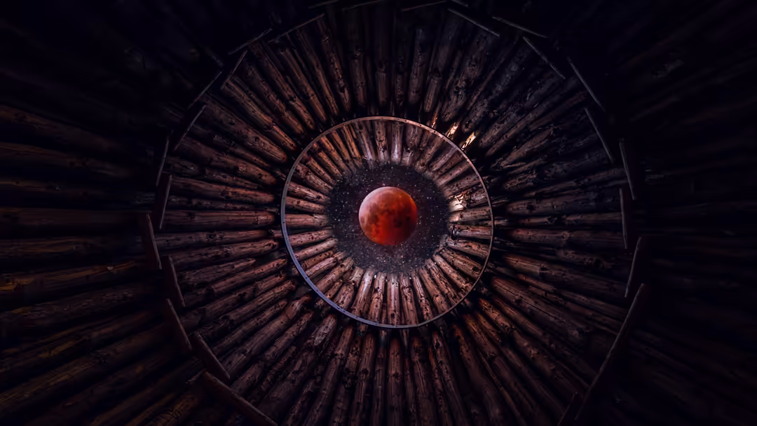 Abstract surreal artwork featuring a glowing blood-red moon at the center of concentric wooden circular rings radiating outwa