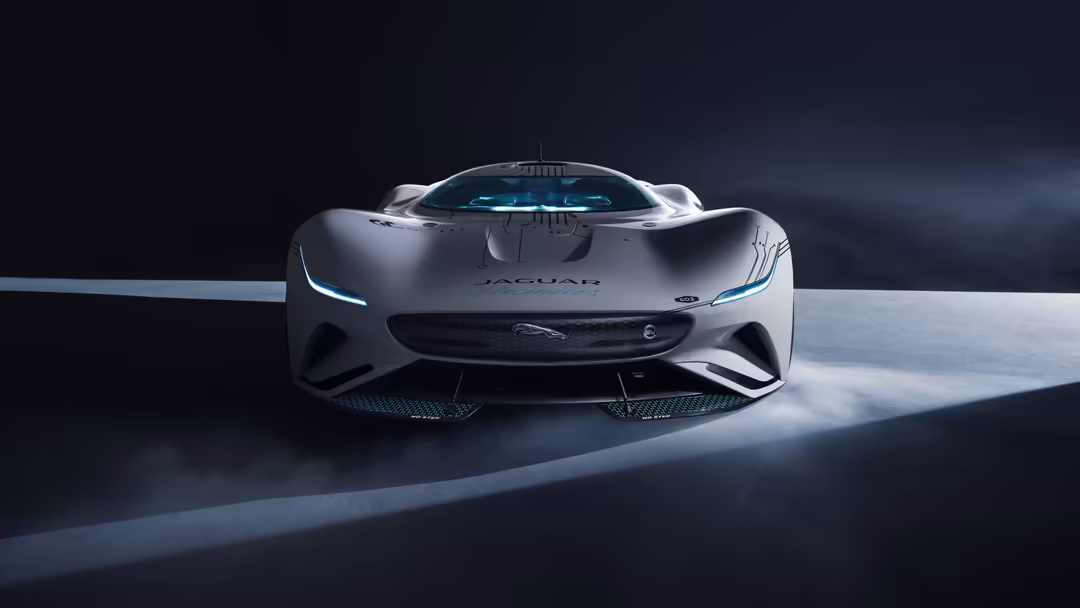 Sleek silver Jaguar Vision Gran Turismo SV concept car with blue accents displayed in dramatic lighting against dark backgrou