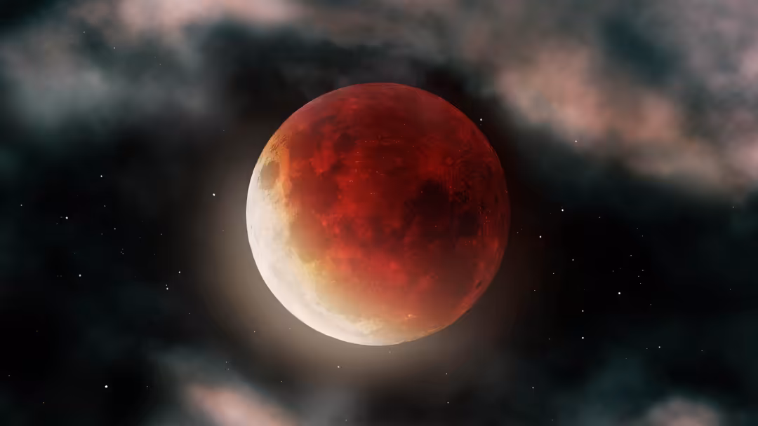 A blood moon lunar eclipse glowing red and white against a dark starry sky with clouds, creating a dramatic celestial phenome