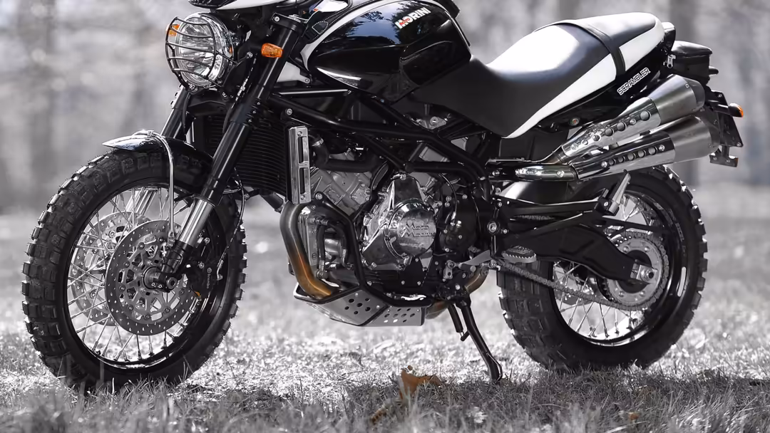 Black and white motorcycle cruiser with dual exhaust pipes, chrome details, and classic styling parked on gravel ground