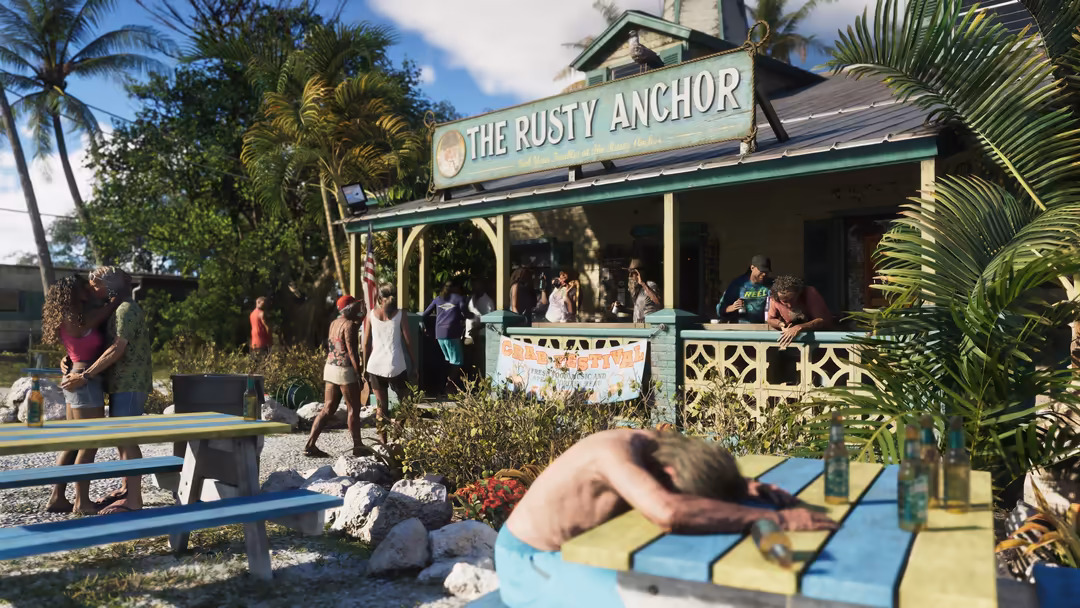 Rusty Anchor beach bar with palm trees, colorful picnic tables, and visitors enjoying the tropical coastal atmosphere under b