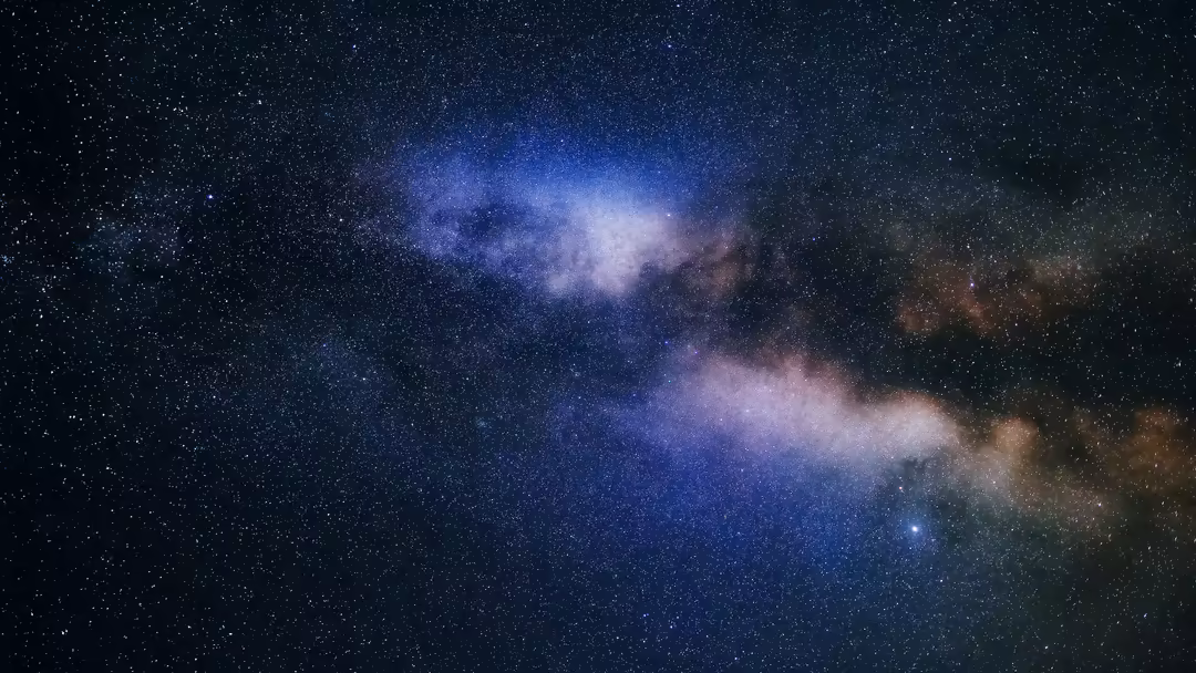 Milky Way galaxy with luminous blue and purple nebula clouds scattered across a starfield with countless twinkling stars