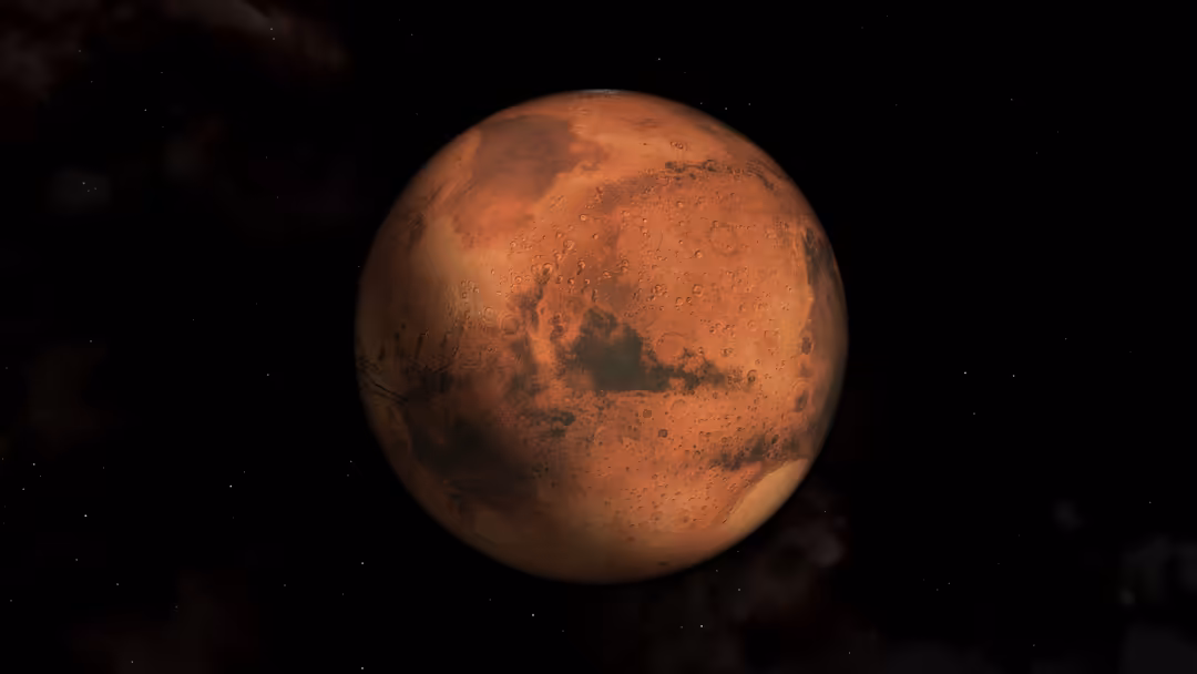 Close-up view of Mars with its distinctive rusty red surface, craters, and dark regions against a black starry space backgrou
