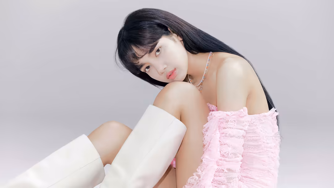 Portrait of Lisa with long black hair and bangs wearing pink textured fabric and white sleeve, tilting head with contemplativ
