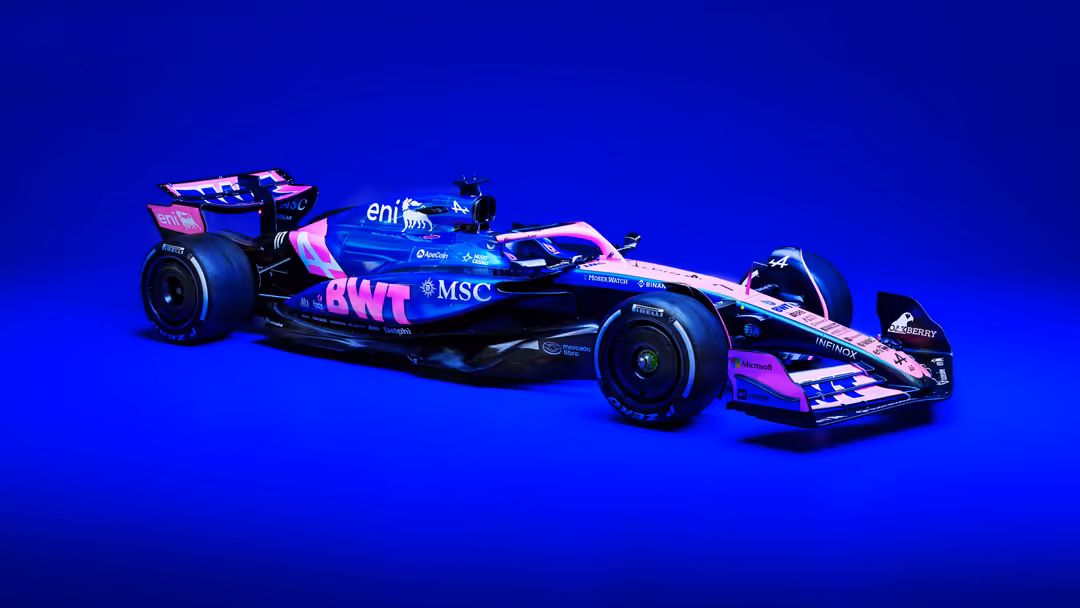 Modern Formula One racing car in vibrant blue and pink livery positioned against brilliant blue background with dramatic ligh