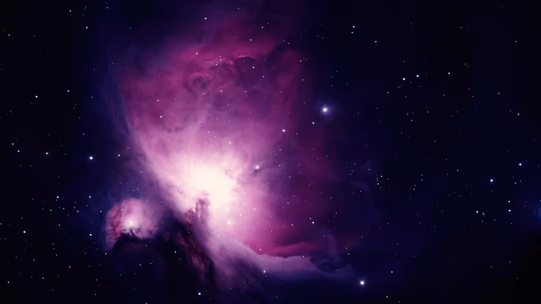 Glowing purple and magenta Orion Nebula with bright core, swirling gas clouds, and scattered stars against deep black space