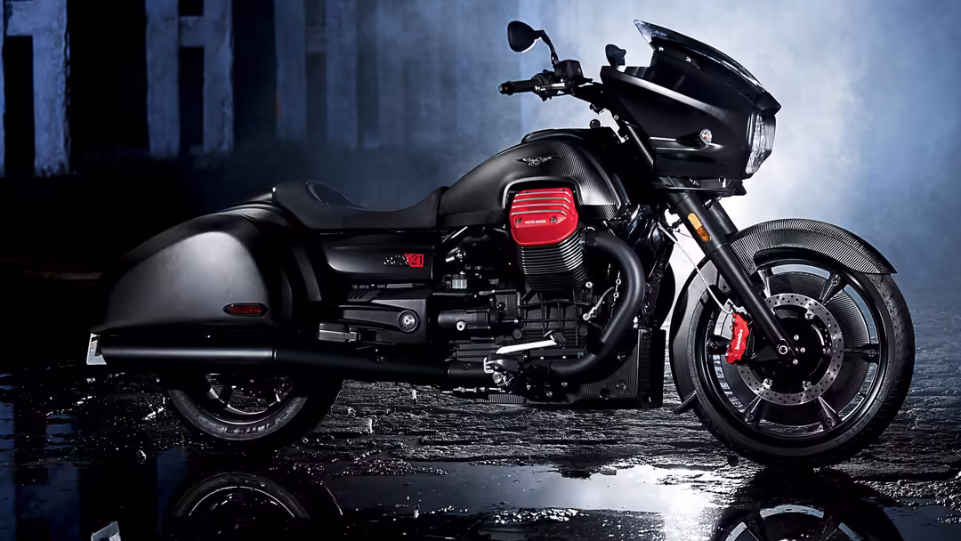 Black motorcycle with sidecar parked on wet pavement in moody urban setting with industrial architecture backdrop and dramati